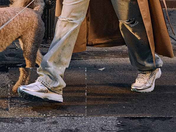 A person wearing Brooks shoes and jeans walks a dog