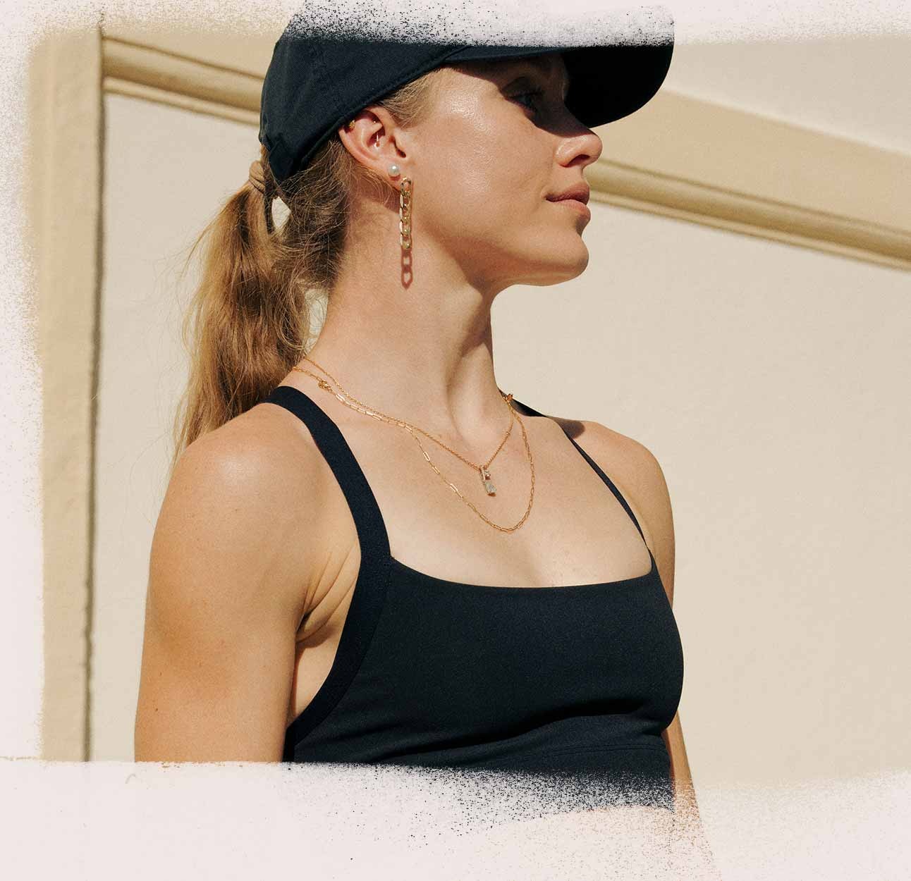 A woman wearing a Brooks sports bra and hat looks to the side